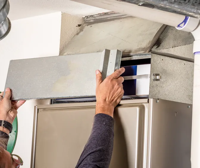 A pleated air filter being slid into the filter slot of a home air handler