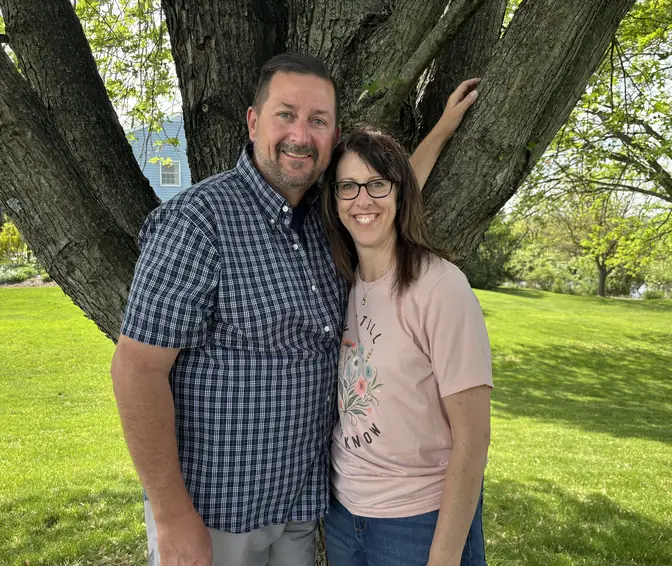 Dan and Michelle McCauley, the owners of Guardian Solutions Plus, standing together outdoors beneath a tree