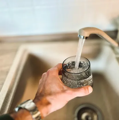 A glass being filled with clear water from a kitchen tap